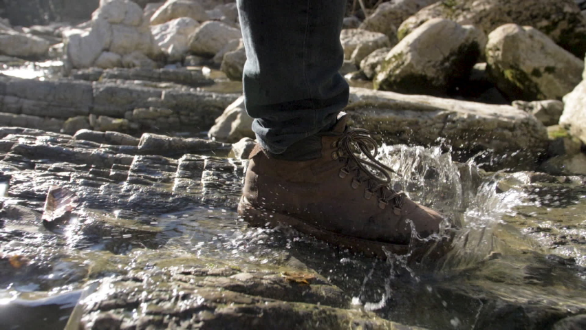 Close-Up Traveler Man Walks Along the River to Mountains. Hike in Boots Go Steps Stone Road on Background a Beautiful Landscape. Travel Concept Active People on the One Way to Move Forward Slow Motion | Shutterstock HD Video #1066814188