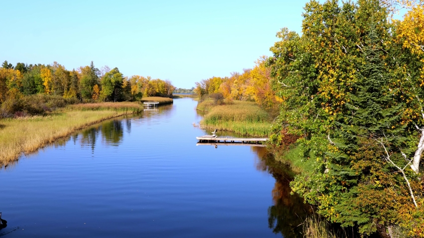 Mississippi River and two canoes head north toward Bemidji Minnesota near highway 2 with zoom in. Beautiful autumn colors in the trees along the river, a few miles from the source at Lake Itasca
