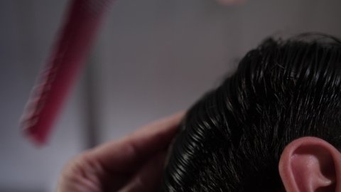 The master makes a cut with scissors and and a pink comb client to a man in a barber shop. A training video. Video for masters of hairdressers. High quality 4k footage