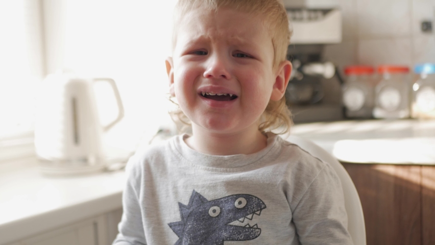 The child sits crying, dissatisfied. The boy is offended, upset. Black teeth.