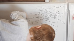 The child draws on the refrigerator with a black felt-tip pen. View from the back. Little boy learns to paint, creativity. Vertical. - Powered by Shutterstock - Get 15% off with code: PIKWIZARD15