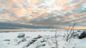 A 4K time lapse of cloud movement with landscape view of a frozen sea and stones during the sunset