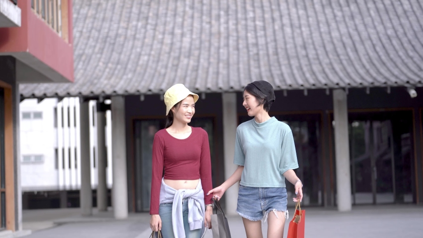 asian happy women walking and holding shopping bag at at outdoor space. Concept fashion girls shopping lifestyle.