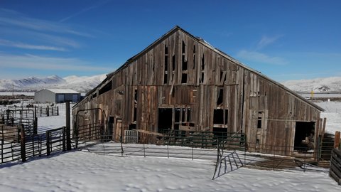 Camera Rises Above Old Weathered Barn in Winter Snow - Aerial Drone