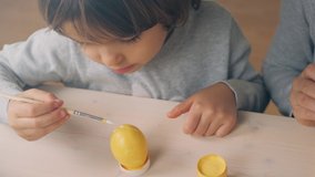 Happy Easter Holiday. Beautiful kids paint and decorate eggs for a traditional spring dinner at home. Little girl playing, drawing and decorating a yellow colored egg - Powered by Shutterstock - Get 15% off with code: PIKWIZARD15