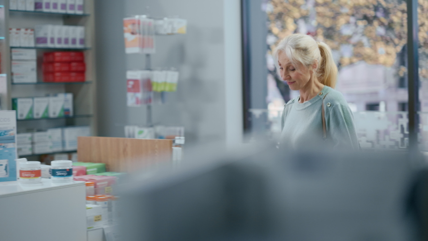 Pharmacy Drugstore Checkout Counter: Black Male Pharmacist Explains Use and Manual for Prescription Medicine Beautiful, Senior Female Customer Paying Using Contactless Credit Card to Terminal | Shutterstock HD Video #1066836151