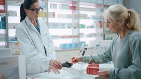 Pharmacy Drugstore Checkout Cashier Counter: Female Pharmacist Service Beautiful Senior Female Customer Buying Prescription Medicine Package and Paying Using Contactless Credit Card to Terminal - Powered by Shutterstock - Get 15% off with code: PIKWIZARD15