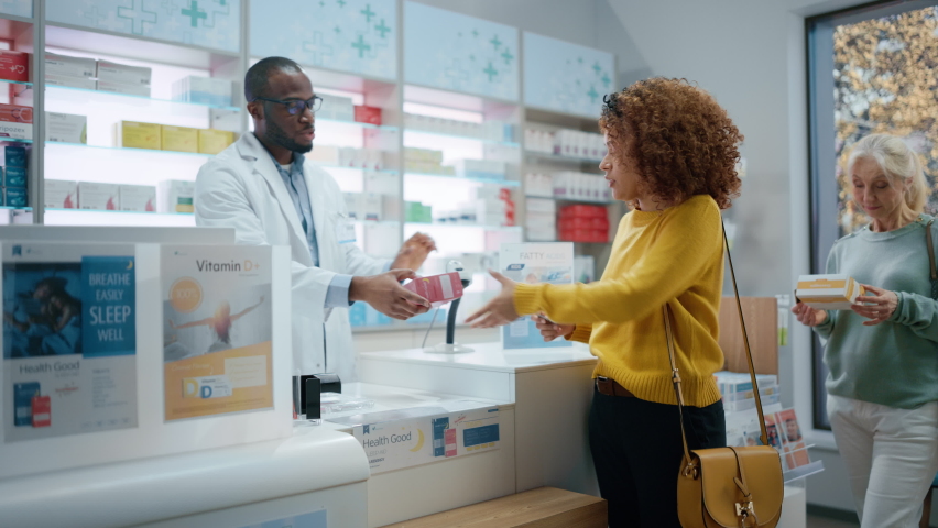 Pharmacy Drugstore Checkout Counter: Professional Black Pharmacist Provides Best Customer Service to Diverse Group of Multi-Ethnic Clients Buying Medicine Paying with Contactless Payment Credit Cards | Shutterstock HD Video #1066836193