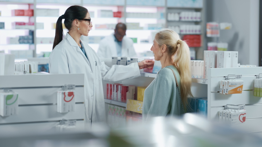 Pharmacy: Professional Caucasian Pharmacist Helping Beautiful Senior Female Customer with Medicine Recommendation, Advice, Talking. Drugstore with Full of Drugs, Pills, Health Care, Beauty Products | Shutterstock HD Video #1066836268