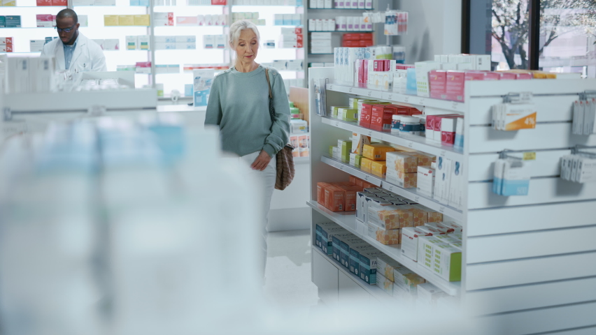 Pharmacy Drugstore: Portrait of a Beautiful Senior Woman Choosing to Buy Medicine, Drugs, Vitamins. Apothecary Full of Health Care Products, Supplement Bottles, Beauty Packages with Modern Design | Shutterstock HD Video #1066836478