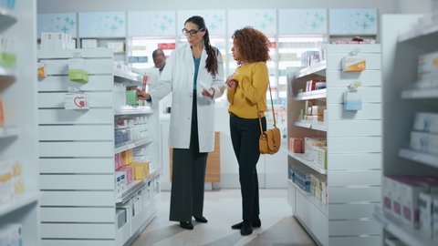 Pharmacy: Professional Caucasian Pharmacist Helping Beautiful Black Female Customer with Medicine Recommendation, Advice, Talking. Drugstore with Full of Drugs, Pills, Health Care, Beauty Products