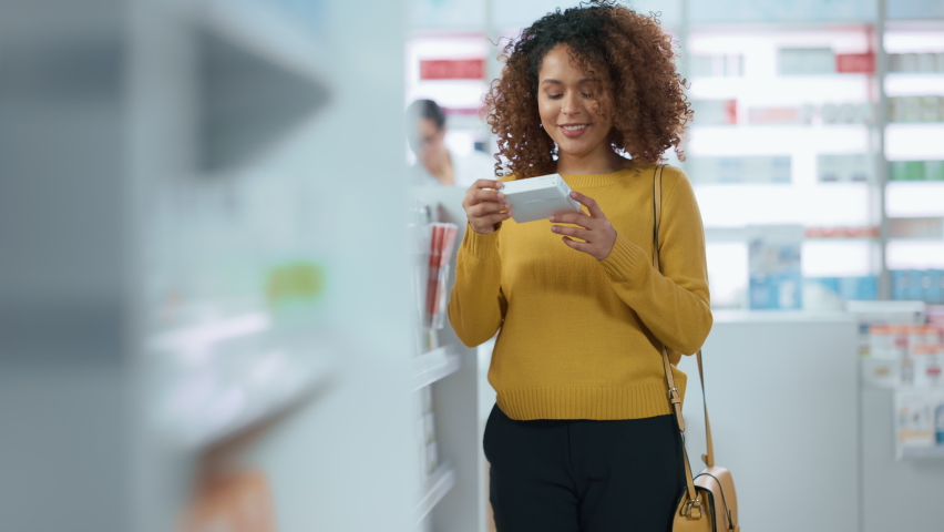 Pharmacy Drugstore: Beautiful Black Young Woman Walking Between aisles and Shelves Shopping for Medicine, Drugs, Vitamins, Supplements, Health Care Beauty Products with Modern Package Design Royalty-Free Stock Footage #1066836583