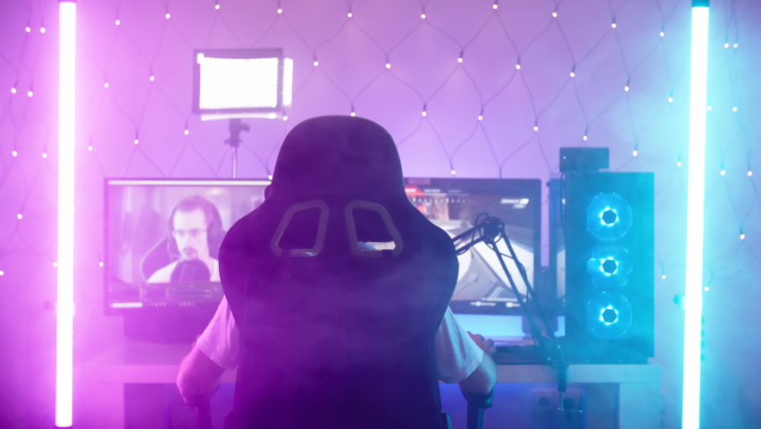 Streamer playing on gaming station with futuristic neon lights and haze 4K