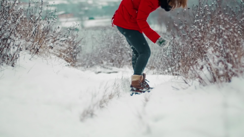 In winter, a young girl slips in her shoes on the snow in a snowfall and could not resist and fell to the ground hitting her head and shoulders hard, from pain and injuries she twisted to the side. Royalty-Free Stock Footage #1066842382