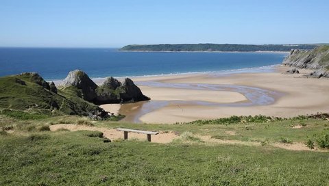 View of Three Cliffs Bay the Gower Peninsula Swansea Wales uk from the east with a wooden bench seat