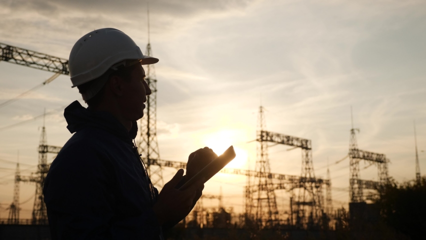 electrical worker silhouette engineer a working with digital tablet, near tower with electricity. energy business technology industry concept. electrical studying reading documents power on tablet Royalty-Free Stock Footage #1066847611