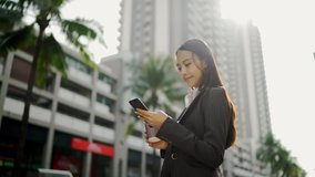 Video Slow-motion. An Asian woman, a beautiful white businesswoman in a black suit, is walking and holding a coffee cup in her left hand. On the side of the road in the city
