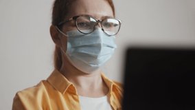 girl in a medical protective mask video call works at a laptop in the office. Stay home social distance coronavirus concept. Woman in medical protective mask working home. social distance