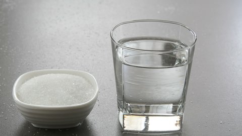 Mixing sugar with water in a glass cup. Sugar water is a healthy drink which provides instant energy.