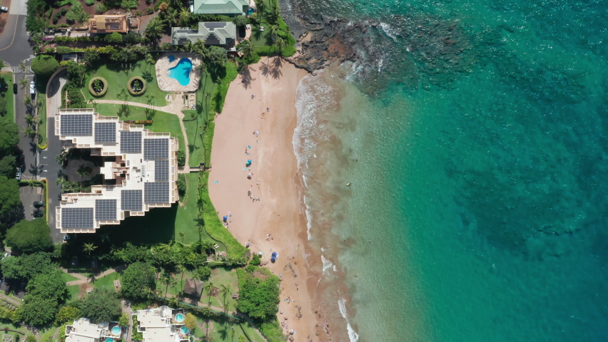 Aerial view on resort building with solar panels on hotel roof. Sustainable electricity generation on sunny tropical island of Hawaii. Travel industry with renewable energy source concept. 4K water
