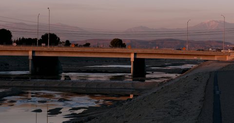 Sunset view of the Santa Ana River as it winds its way through Anaheim with snow capped mountains in the distance.