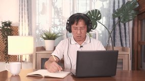 Asian business man in glasses wearing headphones with laptop computer making conference video call, attend webinar or working at home ,Work from home, technology and people concept