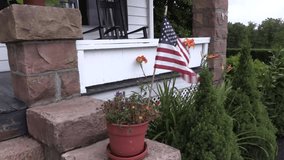 American Flag Waving in Breeze in Front of Quaint Stone Porch - Powered by Shutterstock - Get 15% off with code: PIKWIZARD15