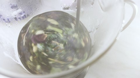 Stir herbal tea in a glass with a spoon.