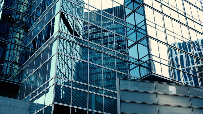 Abstract modern business architecture. Walls made of glass and steel with reflections of buildings and blue sky. Royalty-Free Stock Footage #1066878145