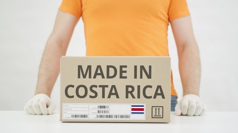 Worker wearing orange uniform puts box with MADE IN COSTA RICA print on the table