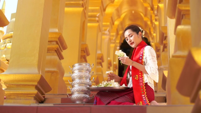 Myanmar women holding flowers at a temple. Southeast Asian young girls with burmese traditional dress visiting a Buddihist temple.