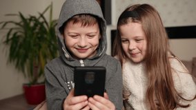 Amazed children watching smart phone, happy young kid using smartphones together, smiling beautiful having fun with phones, see funny video in social network, playing mobile games, reading good news