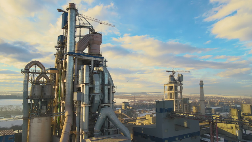 Aerial view of cement plant with high factory structure and tower crane at industrial production area at sunset. Royalty-Free Stock Footage #1066888189