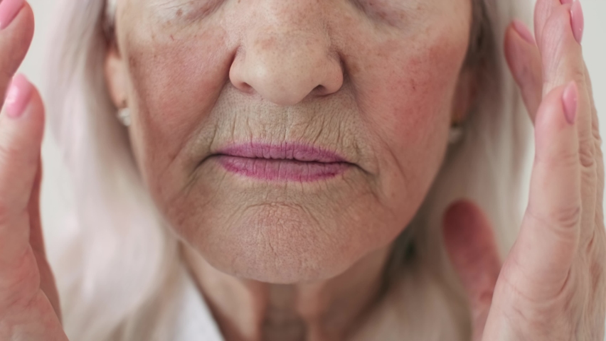 Body Love, Skin Care, Senior Woman, Home Cosmetics, Elderly Age, Cosmetic Procedures. Close-up. 70 year old woman smoothing wrinkles on her face Royalty-Free Stock Footage #1066894939