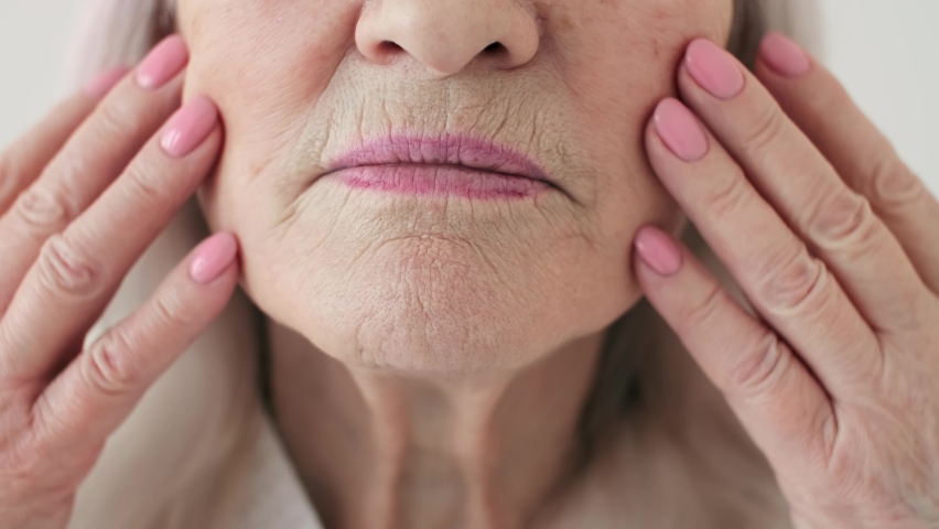 Body Love, Skin Care, Senior Woman, Home Cosmetics, Elderly Age, Cosmetic Procedures. Close-up. 70 year old woman smoothing wrinkles on her face | Shutterstock HD Video #1066894939