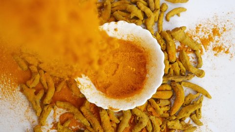 Close shot of dropping turmeric powder, Indian spice being dropped in a bowl