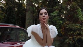 SOCHI, RUSSIA NOVEMBER 16, 2019: Gorgeous bride posing on red retro car, wearing adorable bridal lace dress , beautiful lady looking at the camera, send out tenderness and women charm, girl beauty - Powered by Shutterstock - Get 15% off with code: PIKWIZARD15