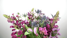 A beautiful selection of flowers arranged in a stunning bouquet. Slow motion zoom footage focusing on centre of colourful floral arrangement. Variety of plants and flower in shades of purple pink blue