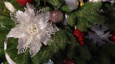 Closeup view 4k video of beautiful green Christmas tree decorated with bright shiny and sparkling different red, silver, white, blue and pink balls, flowers, toys and ribbons. Holiday Xmas background