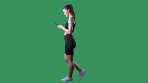 Side view of happy fit young woman using smart phone app. Full body on chroma key green screen.