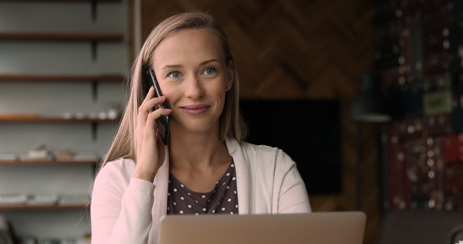Distracted from computer work happy young woman enjoying pleasant conversation by cellphone call, taking speaking chatting with friends or communicating distantly with client, giving consultation. Royalty-Free Stock Footage #1066904872