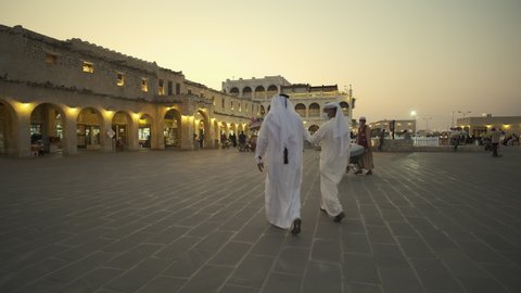 Doha , Qatar- February 2 2021: Souq Waqif main street zooming in  and panning shot at dusk with locals and visitors in the street 