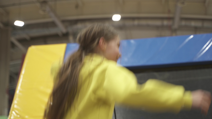 Happy smiling 11 years old kids jumping on trampoline indoors in entertainment center. Active children leisure, jumping and playing on trampoline in sport center. Amusement park. Sport activity.