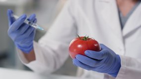 Slow-motion close up of unrecognizable scientist injecting syringe with artificial vitamins to gm tomato in modern laboratory - Powered by Shutterstock - Get 15% off with code: PIKWIZARD15