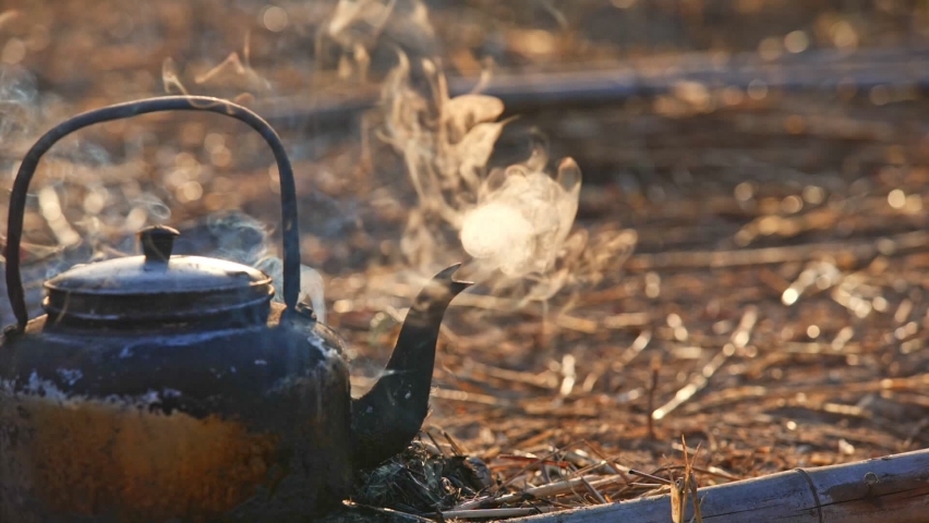 Close up old kettle with steam on the bonfire of countryside 