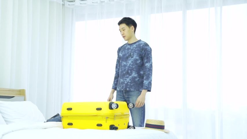 A Man happily packing a bag for traveling. Young man packing bag for holiday. Preparation of travel is also one of the fun and happy.