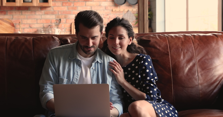 Married couple sit on couch with laptop, family talking, discussing on-line purchase, choose goods, making delivery order, search home design interior ideas on internet using web sites and modern tech Royalty-Free Stock Footage #1066937926