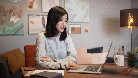 Asian woman using laptop during video conference call. Remote learning during coronavirus lockdown, happy Korean female chat with family and friends home isolation, living room, freelancer home office