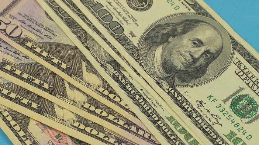 The hand drops a wad of hundred-dollar bills on the playing card table.