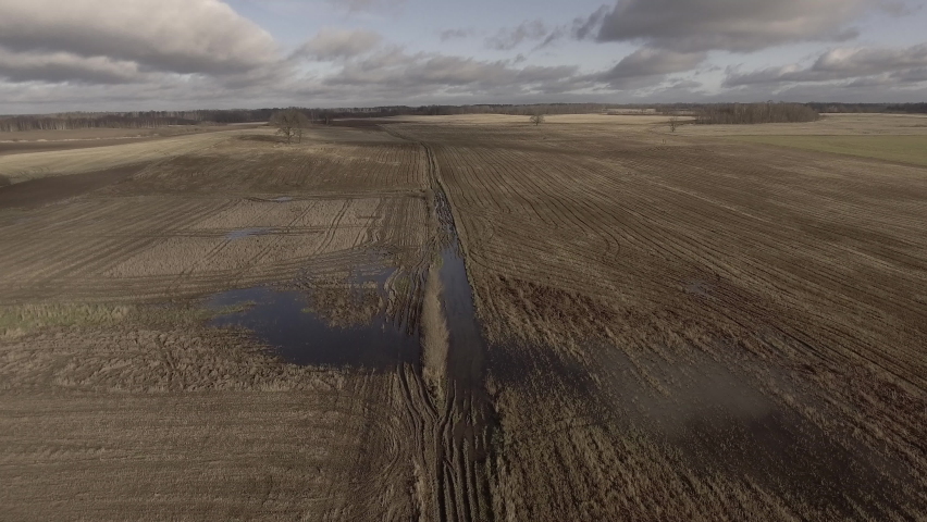 Field in spring, muddy road, plowed land, top view, flight